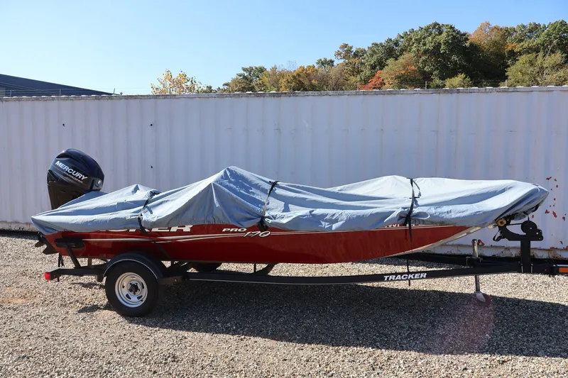 Slide: The Image of 2019 Tracker Pro 170 boat covered, on trailer, outdoors with trees in background. - 42