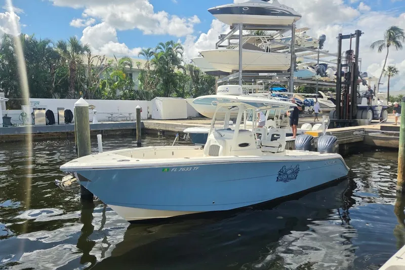Slide: The Image of 2022 Cobia 280 Center Console boat docked at marina under sunny skies. - 1