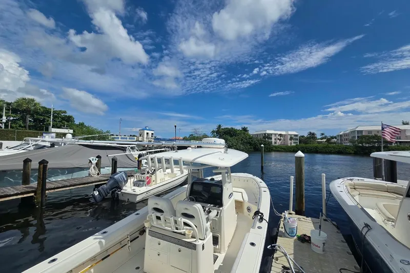 Slide: The Image of 2022 Cobia 280 Center Console boat docked at marina under blue sky. - 10