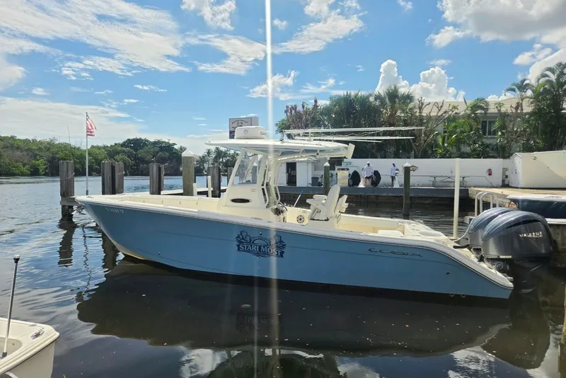 Slide: The Image of 2022 Cobia 280 Center Console boat docked by a marina under a clear blue sky. - 4