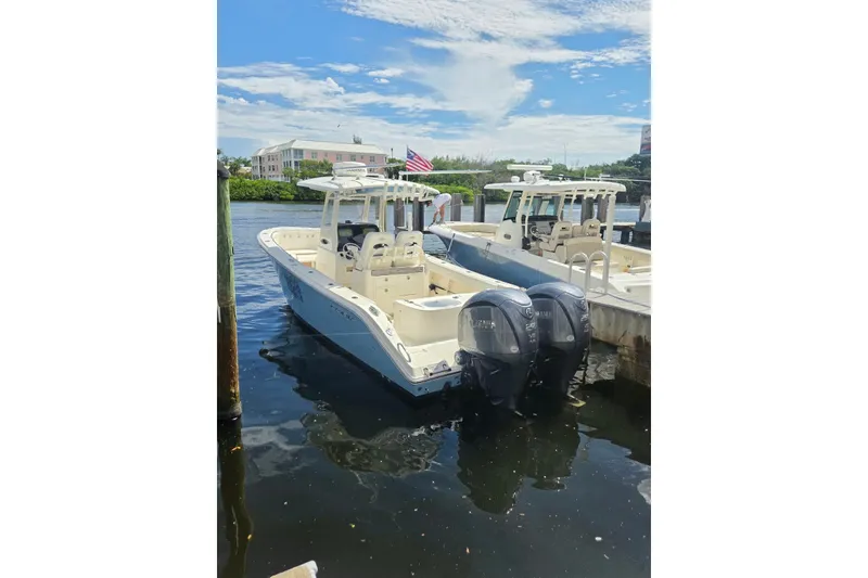 Slide: The Image of 2022 Cobia 280 Center Console boat docked with twin Yamaha engines. - 11