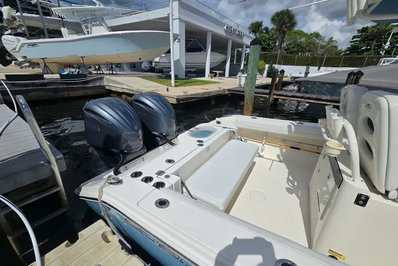 Slide: The Image of 2022 Cobia 280 Center Console boat docked, featuring dual outboard engines. - 20