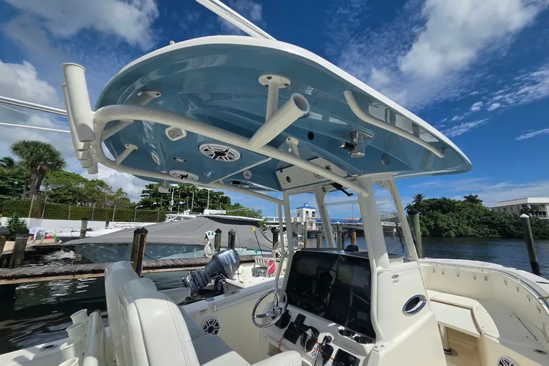 Slide: The Image of 2022 Cobia 280 Center Console boat with blue T-top, docked under clear sky. - 16