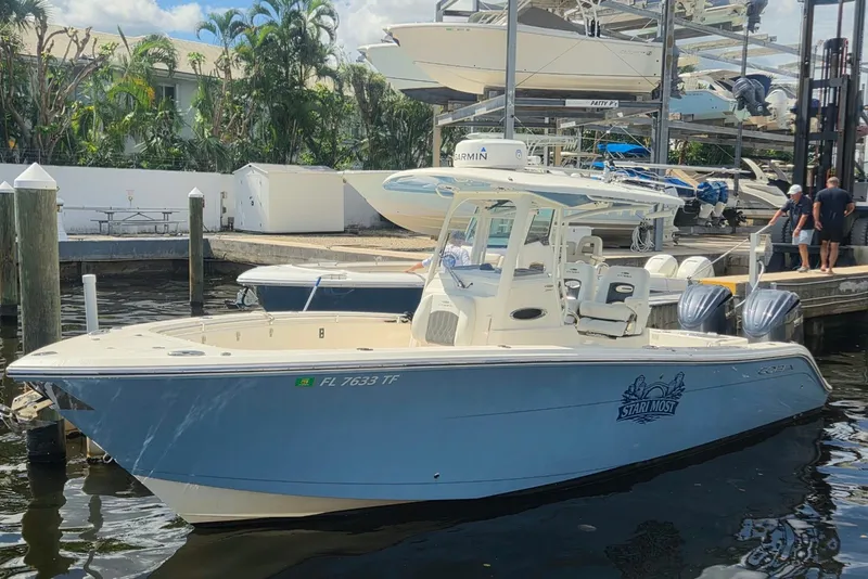 The Image of 2022 Cobia 280 Center Console boat docked at marina with twin engines. - 0