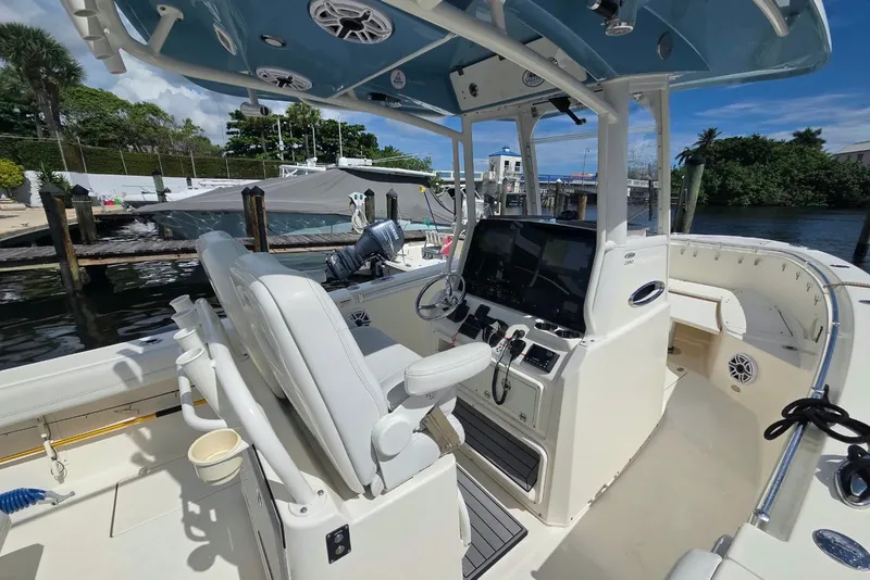 Slide: The Image of 2022 Cobia 280 Center Console boat interior with helm, seating, and dockside view. - 12