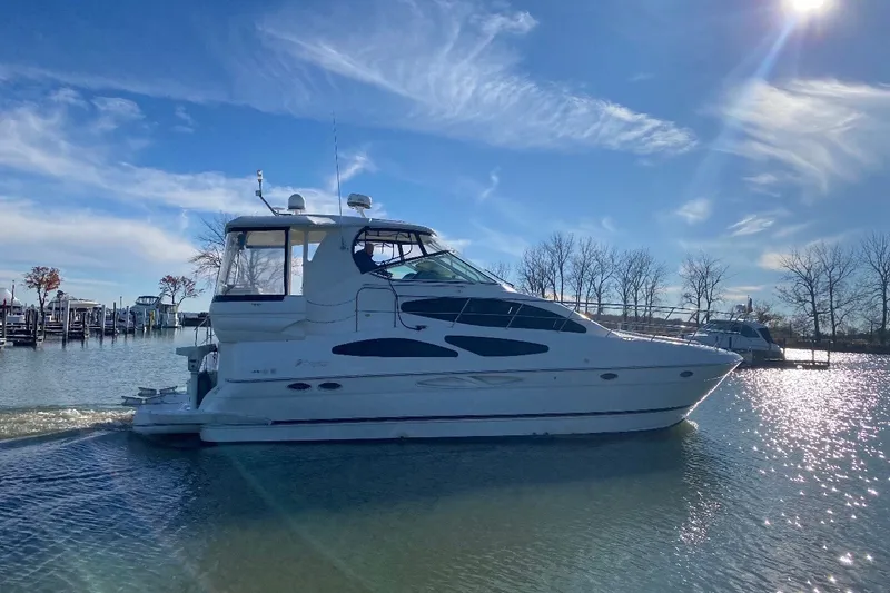 Slide: The Image of 2004 Cruisers Yachts 405 Express Motoryacht on a sunny day, docked near trees. - 2