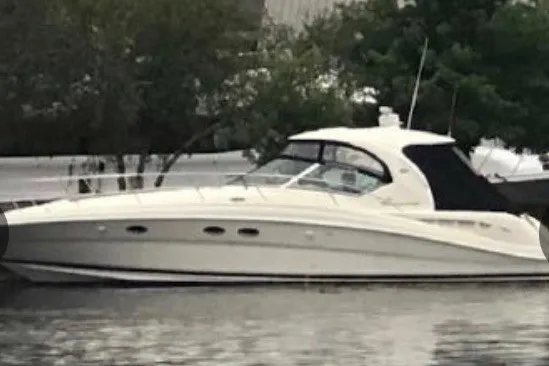 Slide: The Image of 2004 Sea Ray 420 Sundancer yacht docked on calm water, surrounded by trees. - 2