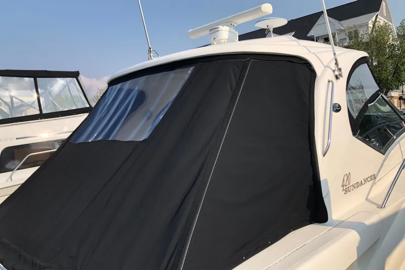 Slide: The Image of 2004 Sea Ray 420 Sundancer yacht with black canvas cover, docked near a house. - 9