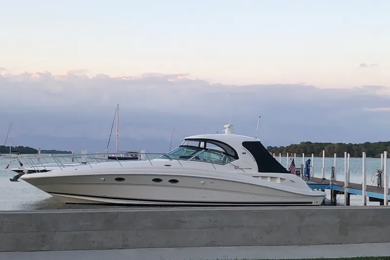 Slide: The Image of 2004 Sea Ray 420 Sundancer yacht docked by a serene waterfront at sunset. - 1