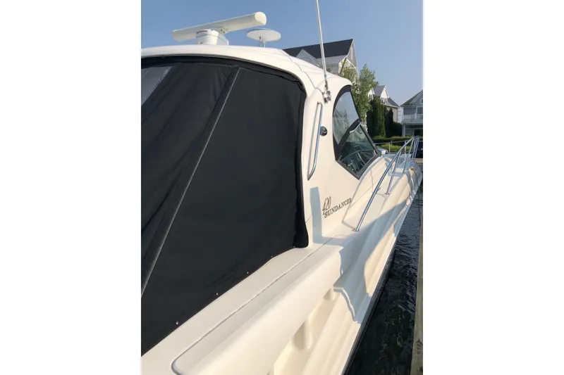 Slide: The Image of 2004 Sea Ray 420 Sundancer yacht docked, featuring sleek design and black canopy. - 10