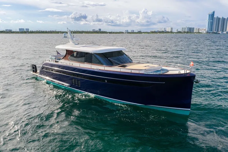 Slide: The Image of Luxury 2021 Steeler 60S yacht cruising on open water with city skyline backdrop. - 7