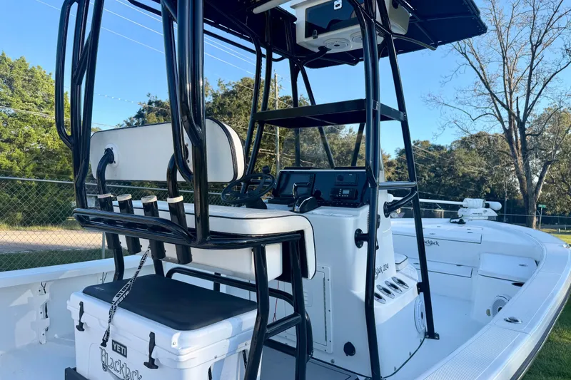 Slide: The Image of 2012 BlackJack 224 boat interior with seating and control panel, surrounded by trees. - 10
