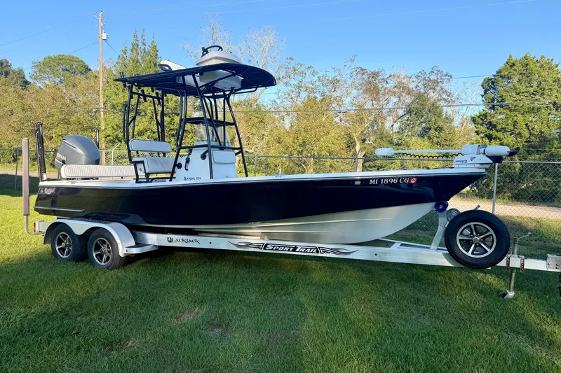 The Image of 2012 BlackJack 224 boat on trailer, parked on grass with trees in background. - 0