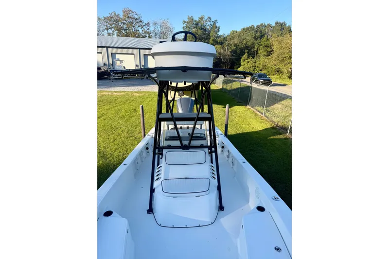 Slide: The Image of 2012 BlackJack 224 boat with elevated helm, parked on grass near a fence. - 4