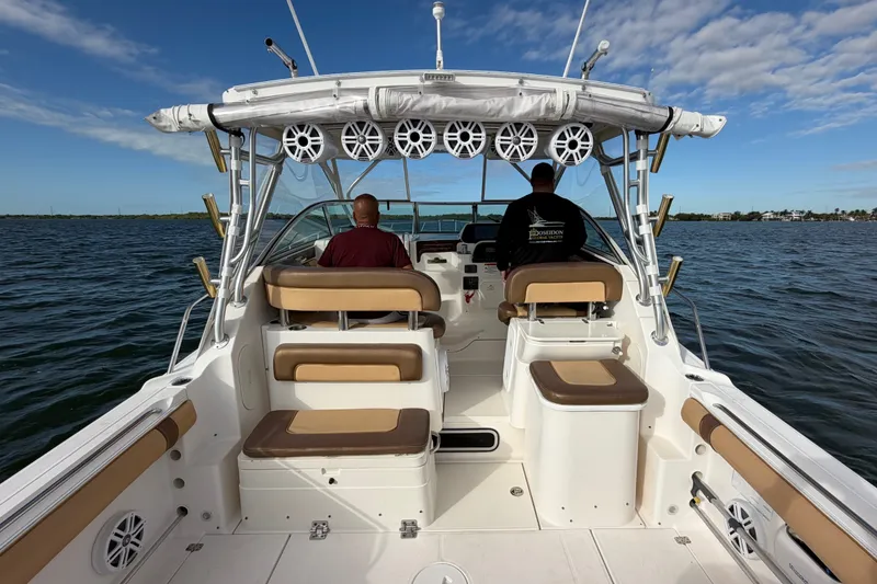 Slide: The Image of 2005 Wellcraft 290 Coastal boat on water, featuring seating and fishing rod holders. - 16