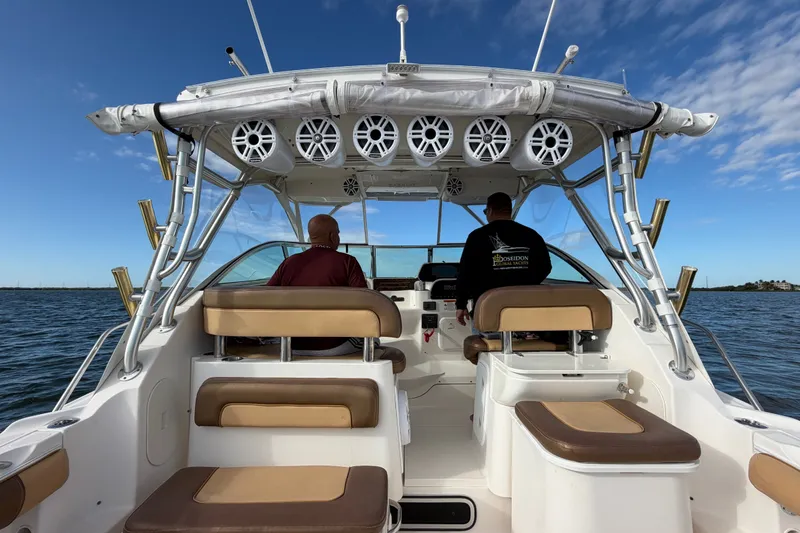 Slide: The Image of 2005 Wellcraft 290 Coastal boat interior with two people, ocean view, and clear sky. - 20