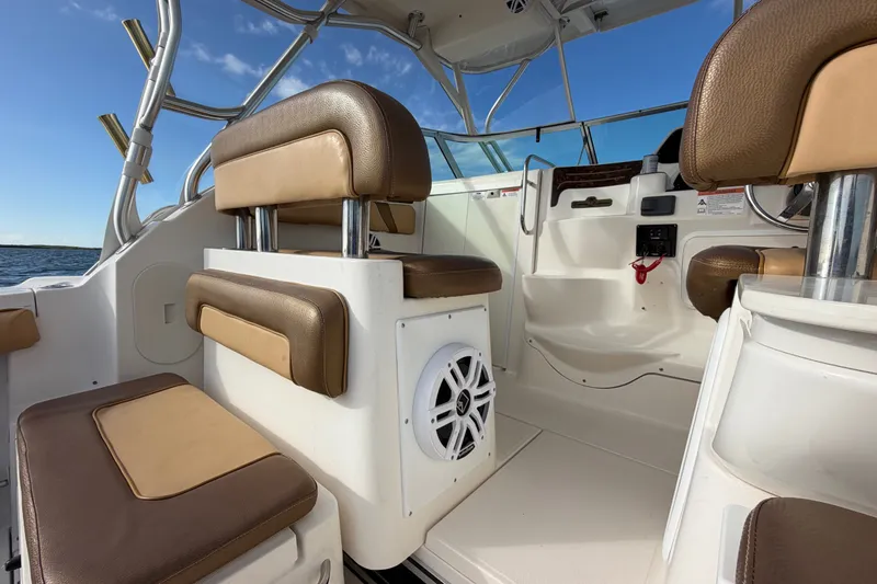 Slide: The Image of 2005 Wellcraft 290 Coastal boat interior with brown seating and speaker, under clear blue sky. - 24