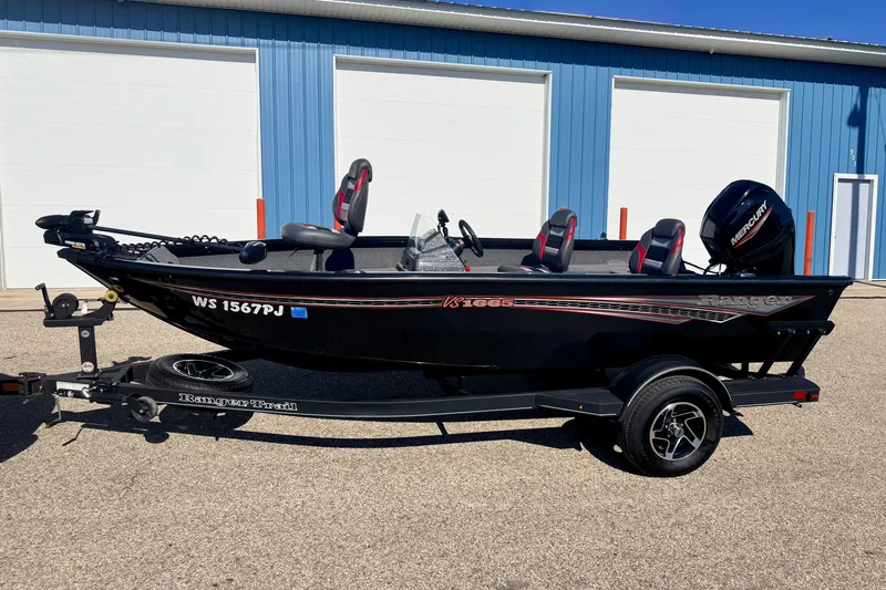 Slide: The Image of 2023 Ranger VS1665T fishing boat on trailer, parked outside blue building. - 2