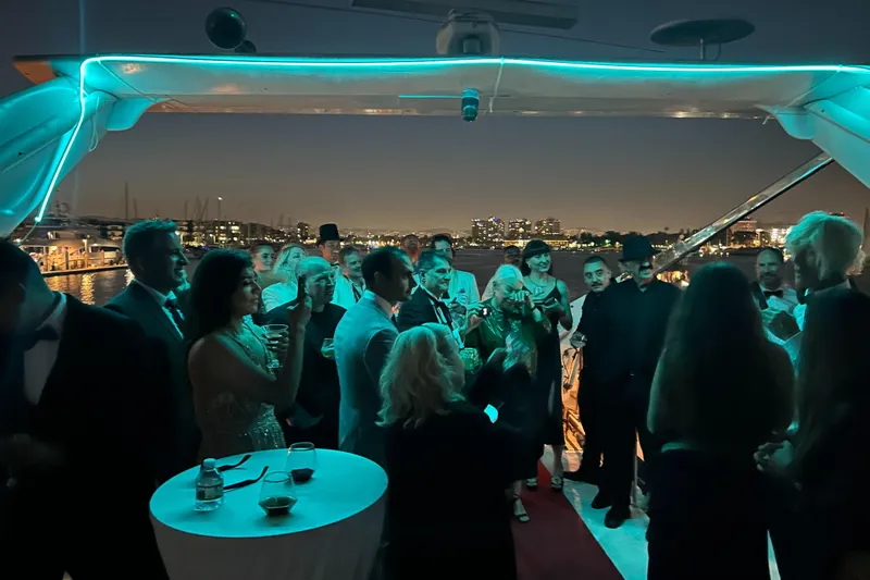 Slide: The Image of Elegant yacht party at night with guests in formal attire, city skyline in background. - 17