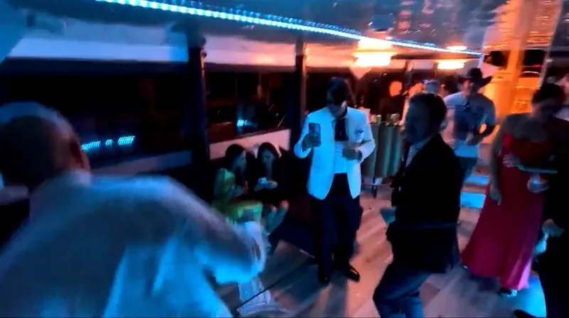 Slide: The Image of People dancing and socializing in a dimly lit party bus with blue lighting. - 14