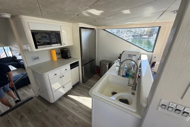 Slide: The Image of Modern boat kitchen with stainless steel appliances, white cabinetry, and large window view. - 39