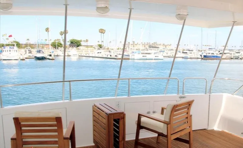 Slide: The Image of View from a 1989 custom boat deck overlooking a marina with wooden chairs and calm waters. - 25