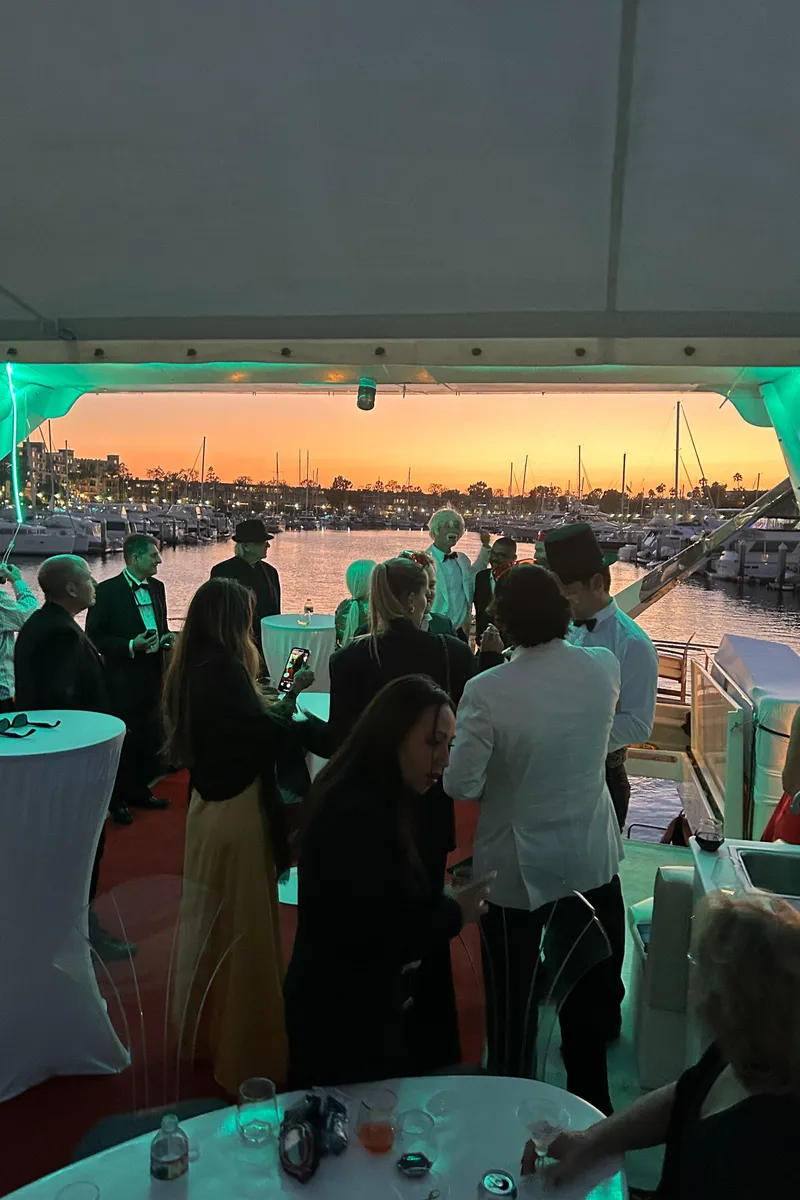 Slide: The Image of People enjoying a sunset yacht party with elegant attire and vibrant lighting. - 18