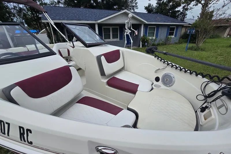 Slide: The Image of 2016 Tahoe 550 TF boat interior with maroon and white seating, parked near a house. - 4