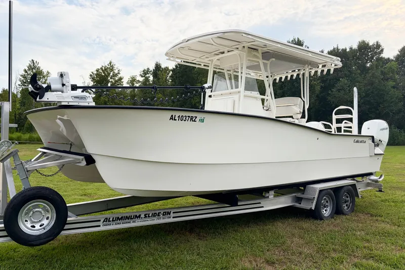 Slide: The Image of 2025 Calcutta 263 boat on trailer, parked on grass, with trees in background. - 1
