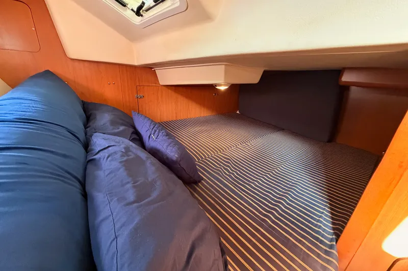 Slide: The Image of Cozy cabin interior of 2009 Hunter 33 sailboat with striped bedding and blue pillows. - 44