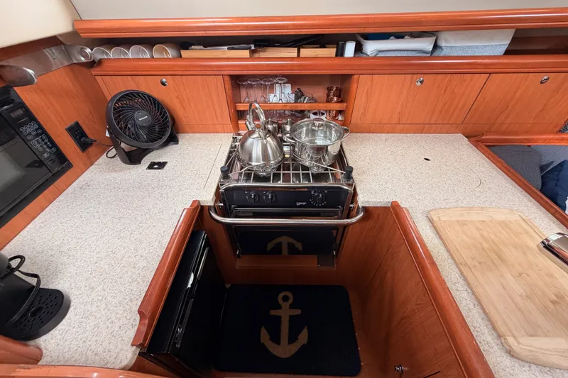 Slide: The Image of Compact kitchen in a 2009 Hunter 33 sailboat with stove, fan, and wooden cabinetry. - 39