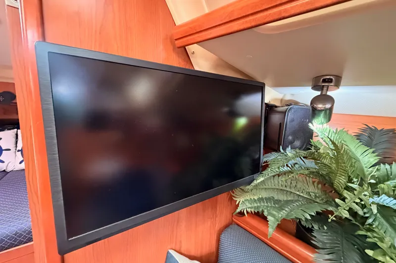 Slide: The Image of Flat-screen TV in 2009 Hunter 33 yacht interior with wooden paneling and decorative plant. - 52