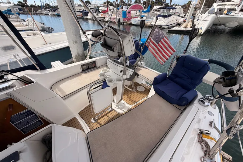 Slide: The Image of Cockpit of 2009 Hunter 33 sailboat with seating, steering wheel, and American flag in marina. - 21