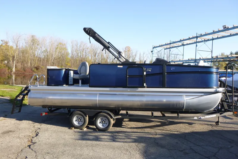 Slide: The Image of 2027 Premier 210 Sunsation Angler 4PT pontoon boat on trailer, parked outdoors. - 1