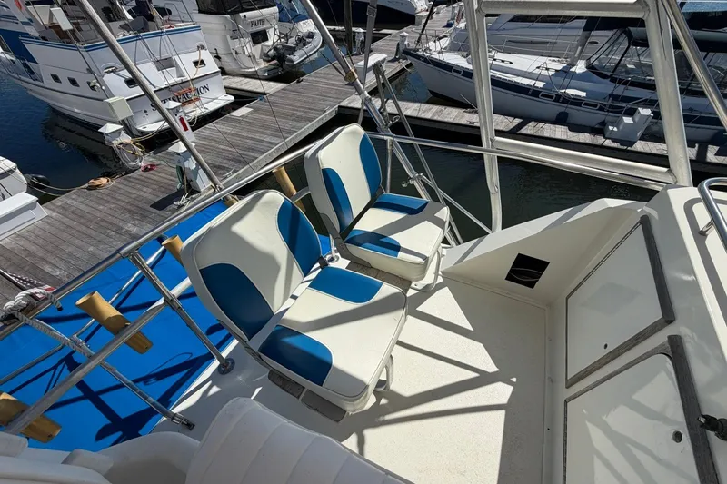 Slide: The Image of Flybridge of 1983 Bertram 38III Convertible with blue and white seating at marina. - 30