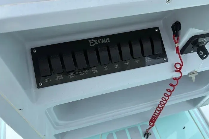 Slide: The Image of Control panel of 2024 Exuma 22 boat with labeled switches and safety cord. - 22