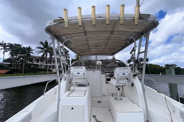 Slide: The Image of 2000 Shamrock 290 Walkaround boat with canopy, docked near waterfront homes and palm trees. - 16