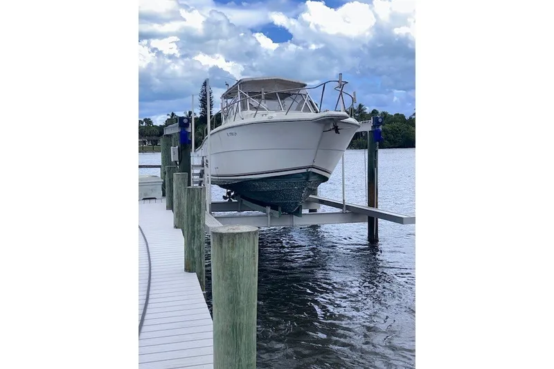 The Image of 2000 Shamrock 290 Walkaround boat on lift at dock, under cloudy sky. - 3