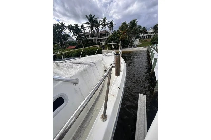 Slide: The Image of 2000 Shamrock 290 Walkaround boat docked near waterfront homes and palm trees. - 13