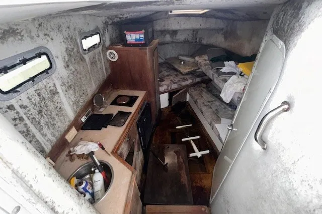 Slide: The Image of Interior of a 2000 Shamrock 290 Walkaround boat, featuring a compact cabin with kitchenette and seating. - 5