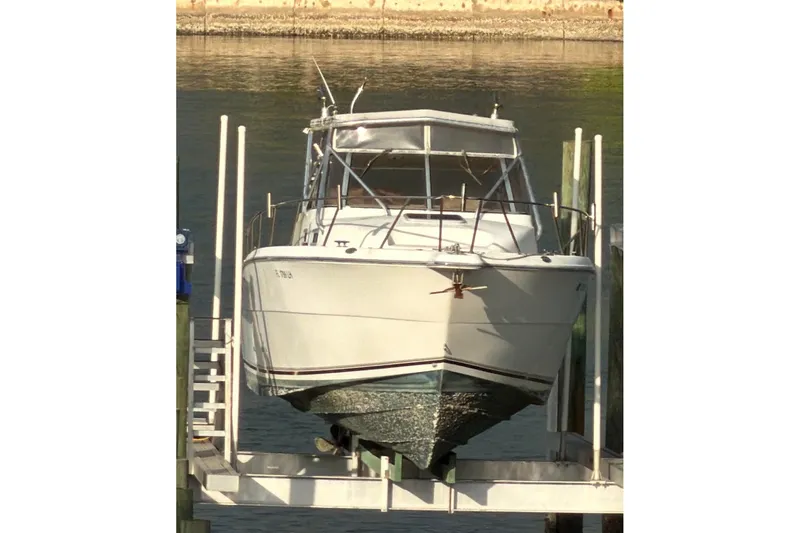 Slide: The Image of 2000 Shamrock 290 Walkaround boat on lift, docked by calm waters. - 6