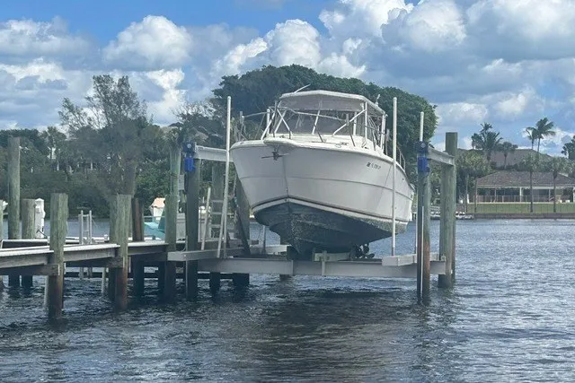 Slide: The Image of 2000 Shamrock 290 Walkaround boat docked on lift under cloudy sky. - 2
