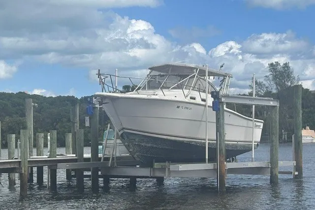 Slide: The Image of 2000 Shamrock 290 Walkaround boat docked on a lift under a cloudy sky. - 9