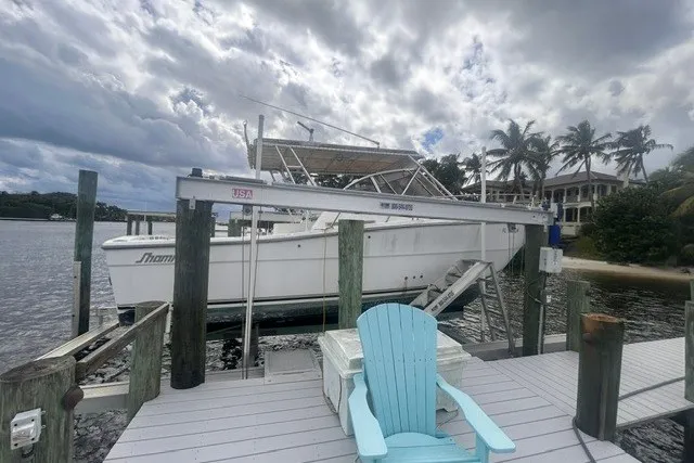 Slide: The Image of 2000 Shamrock 290 Walkaround boat docked by a waterfront with palm trees. - 15
