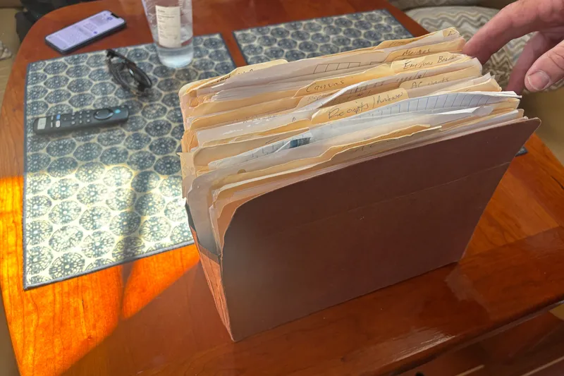 Slide: The Image of Box of organized folders on a wooden table, next to a remote and glasses. - 16