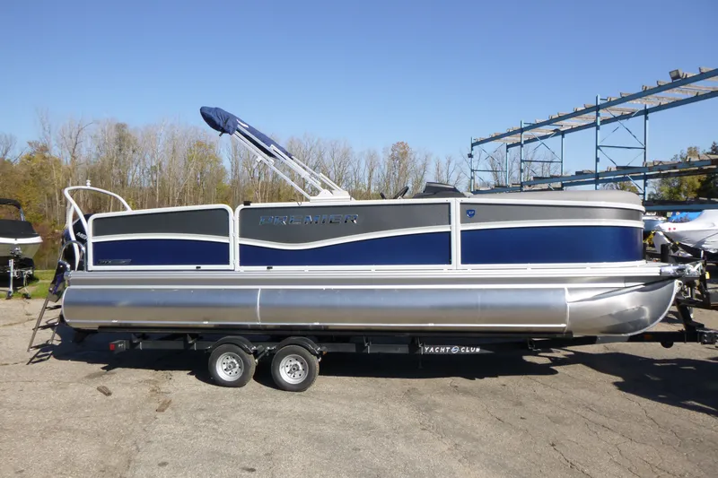 Slide: The Image of 2027 Premier 230 Sunsation Angler 2PT pontoon boat on trailer, parked outdoors. - 1