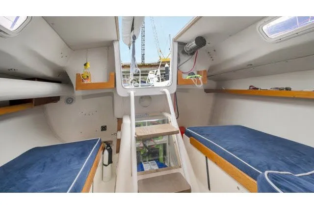Slide: The Image of Interior of 2005 J Boats J/100 sailboat with blue cushioned seating and wooden accents. - 24