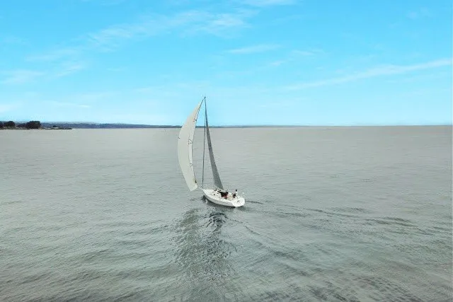 Slide: The Image of Sailboat J/100 by J Boats (2005) gliding on open water under clear blue skies. - 38