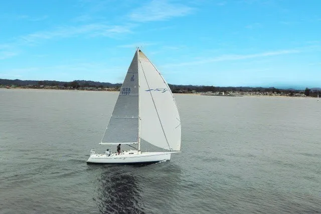 Slide: The Image of Sailboat J/100 from 2005 cruising on calm waters under a clear blue sky. - 2