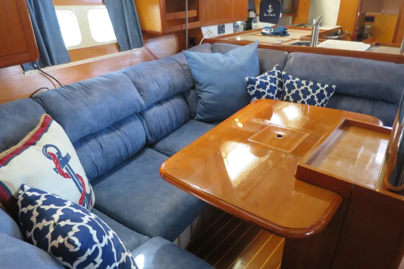Slide: The Image of Interior of 2000 Hunter Legend 410 yacht with blue cushions and wooden table. - 19